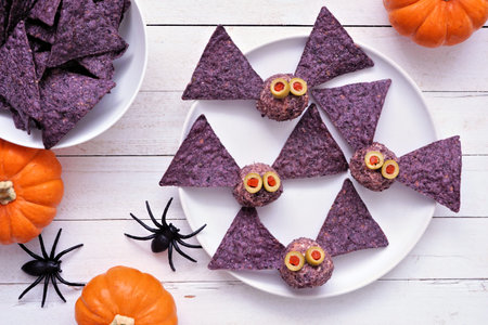 Halloween theme appetizers. Bat cheese balls with purple nachos. Top view table scene against a...