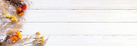 Autumn corner border of dried flowers and grasses. Top view over a white wood banner background. Copy space.の写真素材