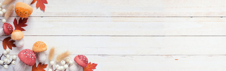 Autumn corner border of leaves, mushrooms and natural decor. Overhead view on a white wood banner...