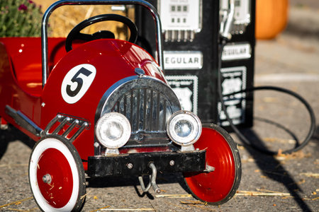 Old red rustic vintage toy race car activity with pump fill station at a local fall fair for...