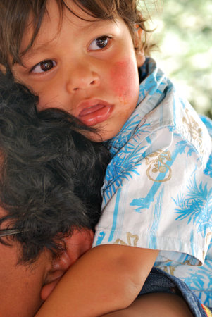 Cute Hispanic boy riding on his dad's shoulders