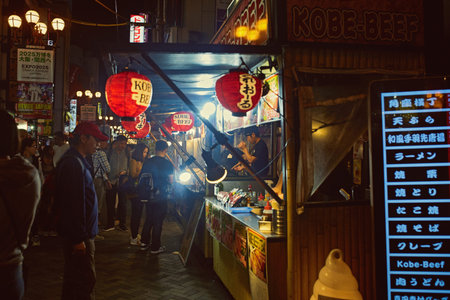 Busy Dotonbori street illuminated at night with patrons buying local street food in Osaka, Japan