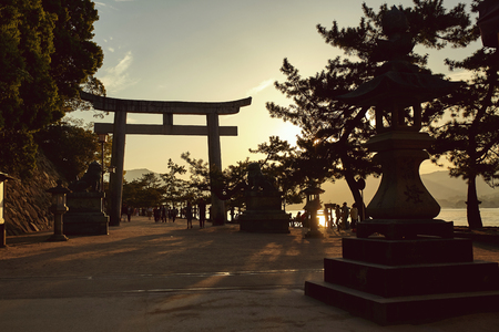 Silhouette of a Torii gate and sculptures on the island of Miyajima at sunset.  Miyajima, Japanのeditorial素材