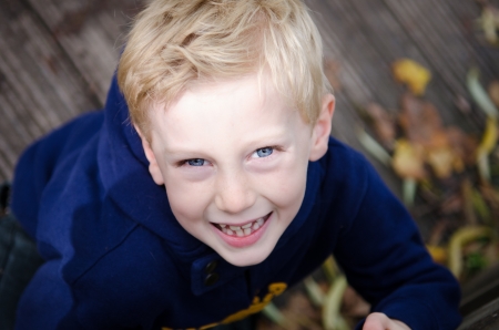 young smiling blonde boy in blue hoody looking upの写真素材