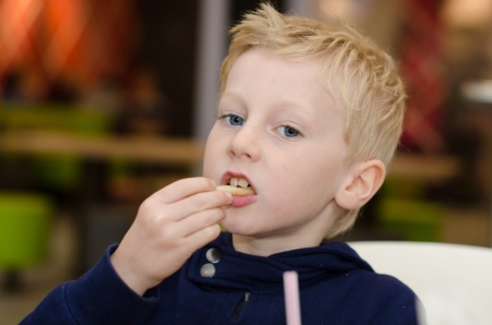 blonde boy kid eating chips friesの写真素材