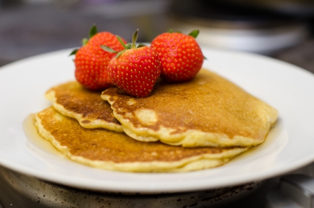 pancakes and syrup with whole strawberries for breakfastの写真素材