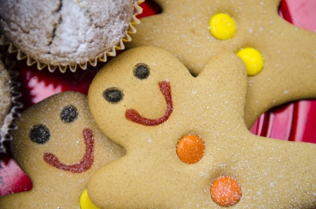smiling gingerbread men with orange and yellow buttons on red Christmas metalic plateの写真素材