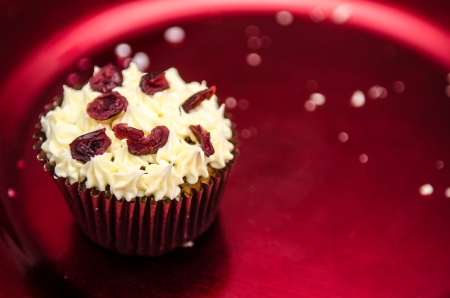 Christmas spiced muffin topped with buttercream and cranberries on a red metalic festive plate, the last oneの写真素材