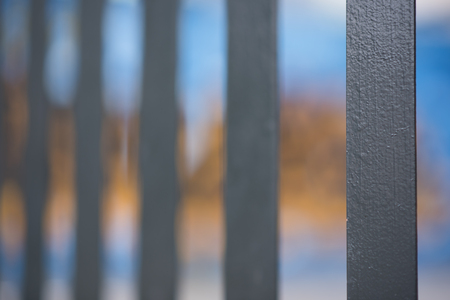 An abstract style shot of black painted palisade fencing with yellow and blue graffiti in the backgroundの写真素材