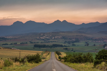 A road leading towards the Drakensberg mountains at sunrise near Clarens, South Africaの写真素材