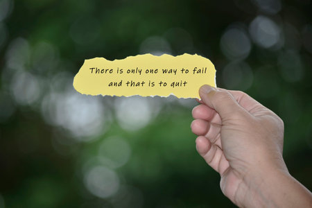 Hands Holding Torn paper with motivational quote and blurred green background. Inspirational quote