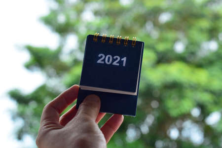 Hands Holding Calendar 2021 with blurred green background.  Happy New Year 2021 Conceptの写真素材
