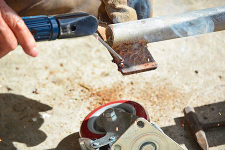 Worker with a welding machine fixing a caster wheels with fiery sparks flying around