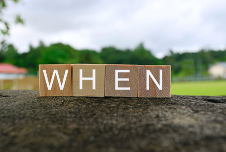 When text on wooden cube block on top of big stone with blurred green and sky backgroundの写真素材