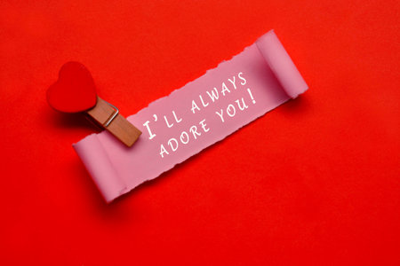 I will always adore you label on torn paper with red paper background. Valentine's Day concept