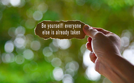 Text Written On Hand Holding Torn Paper With Blurred Green Background. Be yourself concept