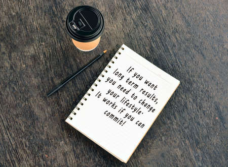 Text on notepad with disposable coffee cup and pen on wooden tableの写真素材