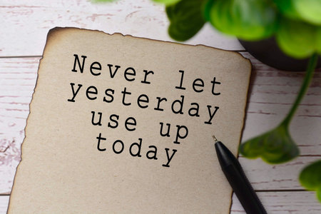 Motivational and inspirational quote on burnt edge brown paper with blurred green plant on wooden...