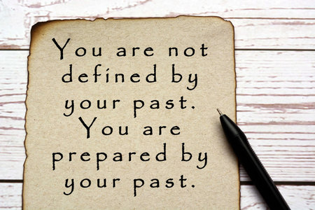 Motivational and inspirational quote on burnt edge brown paper with pen on wooden desk - You are not...