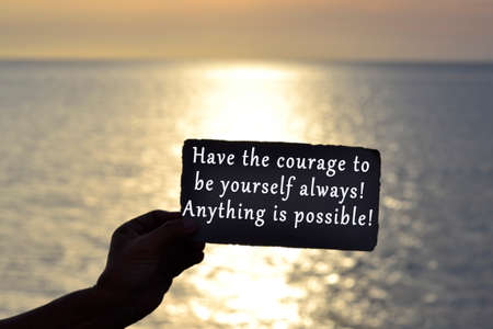 Text on hand holding dark torn paper with blurred background of sunsetの写真素材