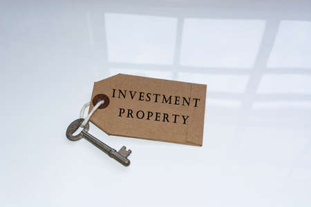 Text on brown tag and key with window reflection on white surface - Investment Propertyの写真素材