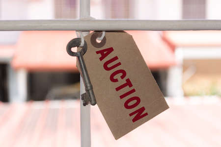 Text on brown paper and key hanging on the window grill with blurred background of houses - Auctionの写真素材