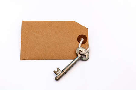 Key and brown paper tag on white background. For text useの写真素材