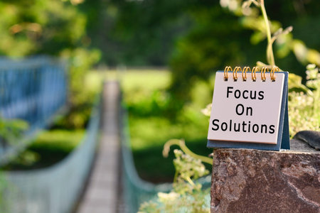 Text written on white note with blurred background of hanging bridge