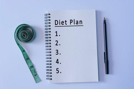 Diet plan text on notepad with pen and measurement tap on white backgroundの写真素材