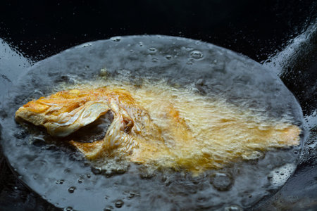 Fresh fish fried in a black pan
