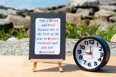 Motivational and Inspirational quote on standing notepad with black alarm clock. Blurred beach...