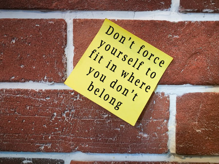 Motivational quote on sticky yellow note on brick wall