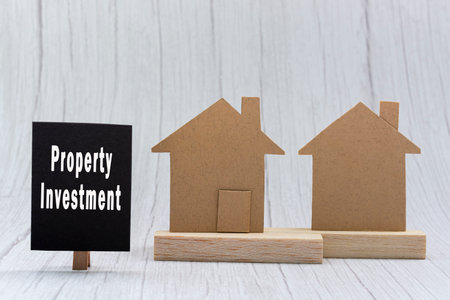 Investment property text on black note with house model on white wooden background. Concept for real estate property investment.の写真素材