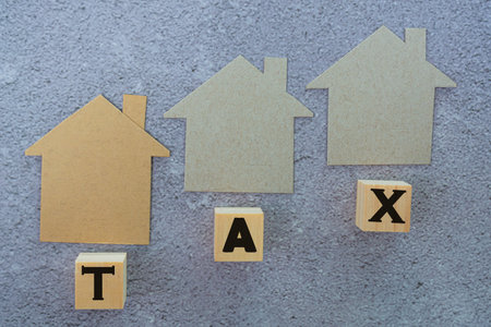 Paper House Model And Tax Text On Wooden Block. Concept for real estate property tax.