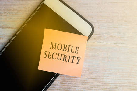 Mobile security text on notepad with smartphone on wooden desk. Password management.の写真素材