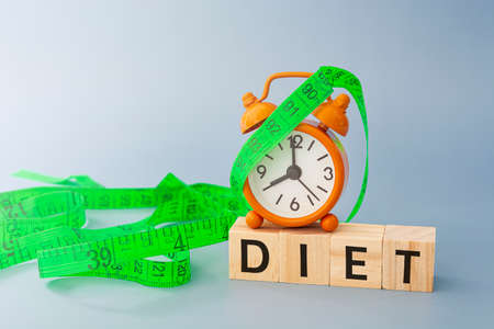 Diet text on wooden block cube with measure tap and orange clock.の写真素材