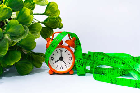 Measure tap with orange clock on white wooden background. Diet concept.の写真素材