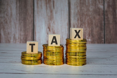 Tax text on wooden blocks and coins on table. Tax concept.