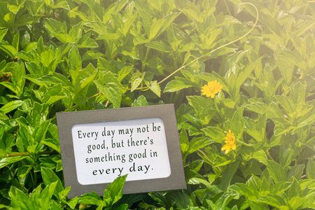 Motivational quote on notepad with blurred green leave and flowers background. Every day may not be...