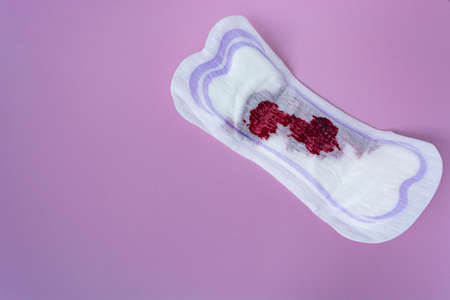 Menstrual blood on a sanitary pad on purple background. Woman hygiene protection. Copy space pattern. Directly above and flat lay.の写真素材