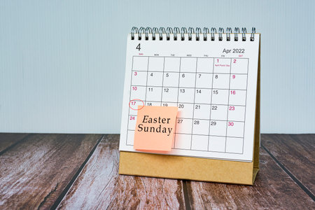 April calendar on wooden desk with date circle and text on sticky note. Easter Sunday on 17th April 2022.の写真素材