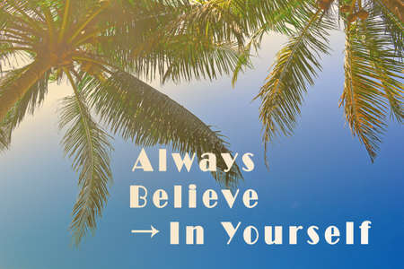 Motivational quote on image of palm trees against blue sky.の写真素材