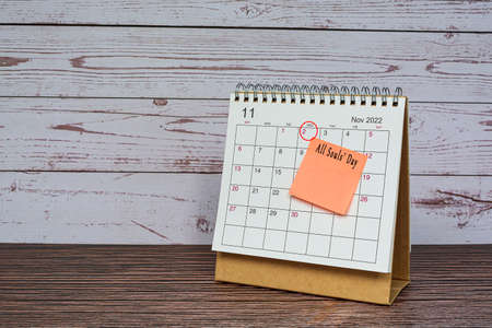 November 2022 calendar on wooden desk with date circle and text on sticky note.の写真素材