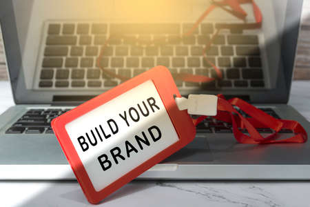 Build your brand text written on red name tag placed on a laptop or notebook..の写真素材