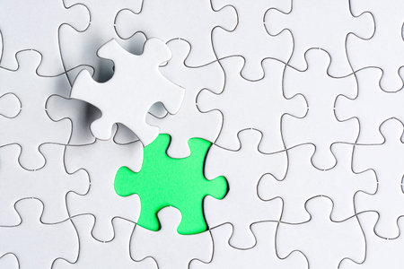 Piece of jigsaw puzzle on green paper. Flat lay, Directly above. Copy space.