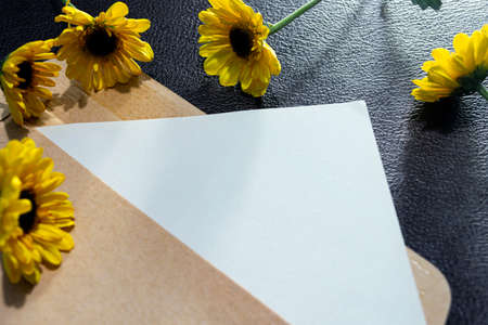 Paper and envelope on wooden surface with sunflowers flat lay with copy space. Directly above.の写真素材