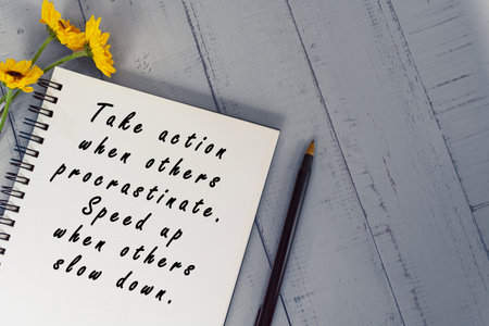 Motivational quote on note book with sunflowers on wooden desk.の写真素材