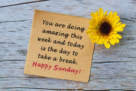 Motivational quote on torn brown paper on wooden surface. Sunday quote.の写真素材