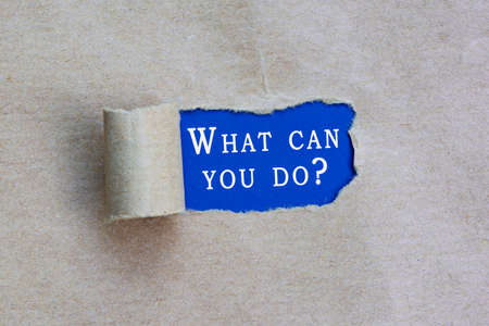 Text on torn hole in the sheet of brown paper on blue background -What can you do.の写真素材
