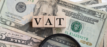 VAT text on wooden cubes with American Dollar-bills. Business and finance concept.